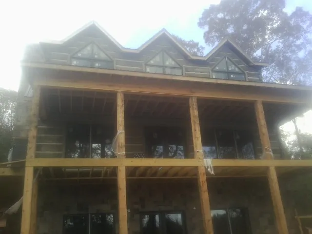 Dormers and porch framing on a large log home under construction — Roof Coating work by our crew in Benson